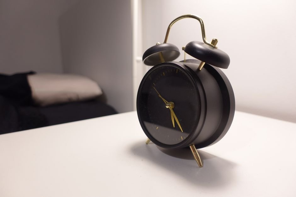 Alarm clock on a bedside table in a dark bedroom at night