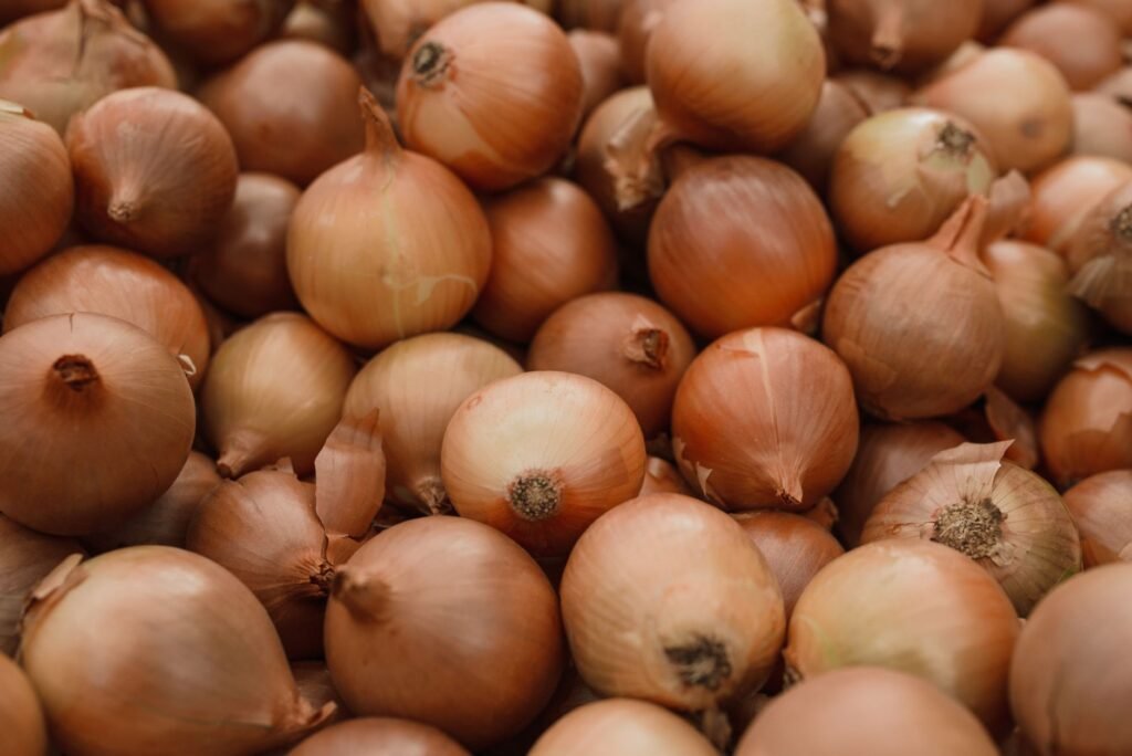 Pile of fresh brown onions, whose sulfur levels affect how much onions make you cry
