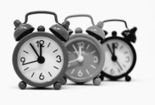 Three vintage alarm clocks, a symbol of why do we have daylight saving time and the twice-yearly clock change