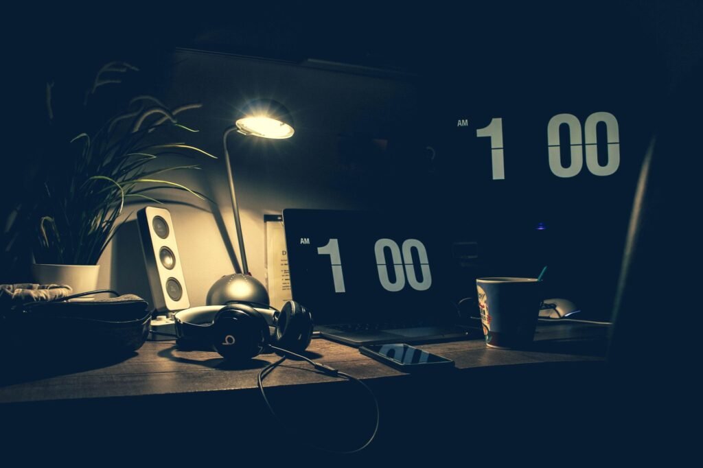 Desk with a laptop and a clock showing 1:00 at night, when the internet slow at night problem usually eases