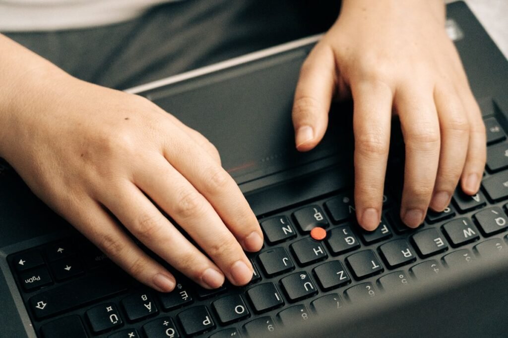 Hands typing on a keyboard, where keyboard letters wearing off is common on the most used keys