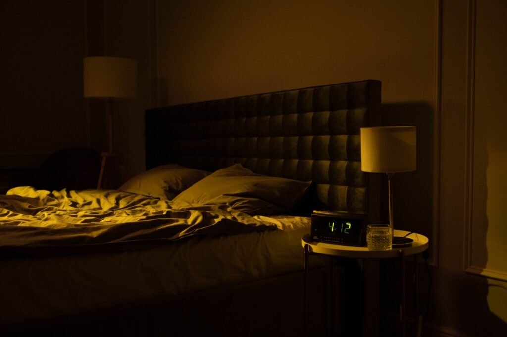 Dim bedroom with an unmade bed and a bedside clock, the scene of waking up at 3am and lying awake